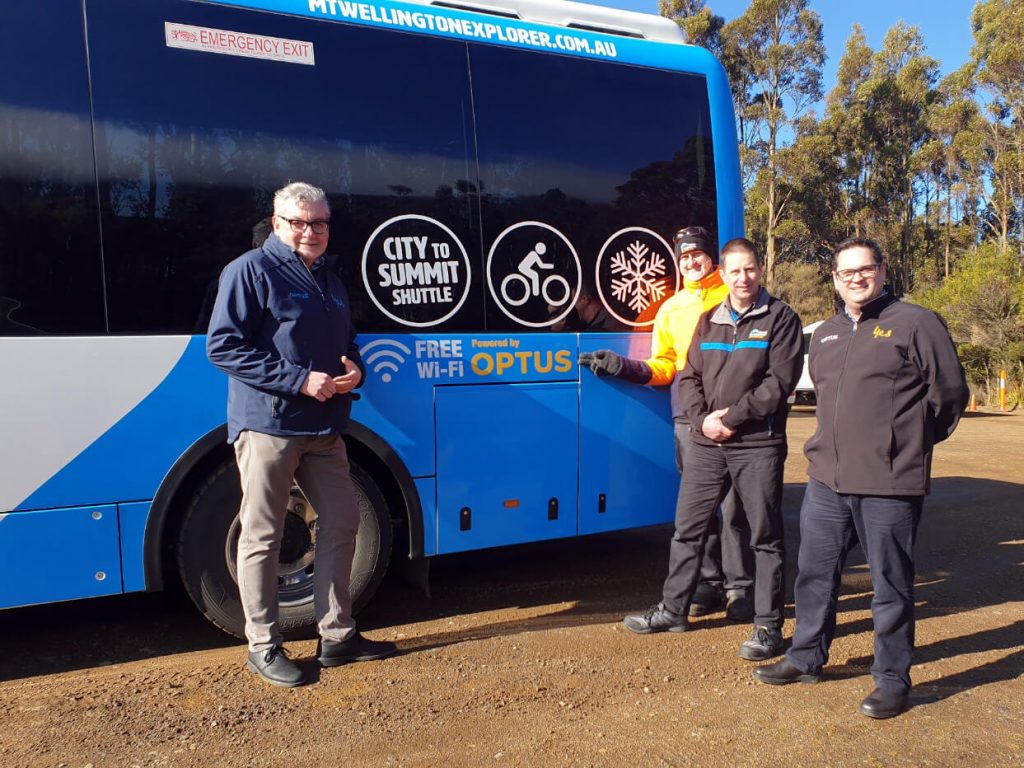 kunanyi/Mt Wellington Explorer Bus and Optus staff members standing next to the Mt Wellington bus.